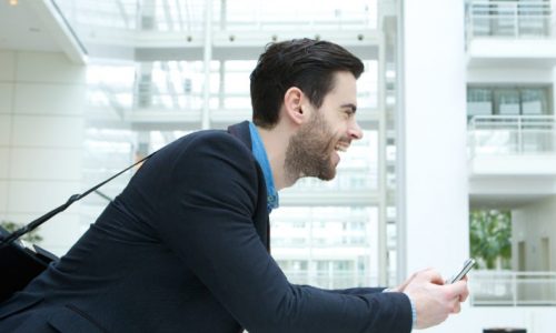 Profile portrait of a young businessman smiling and holding cellphone